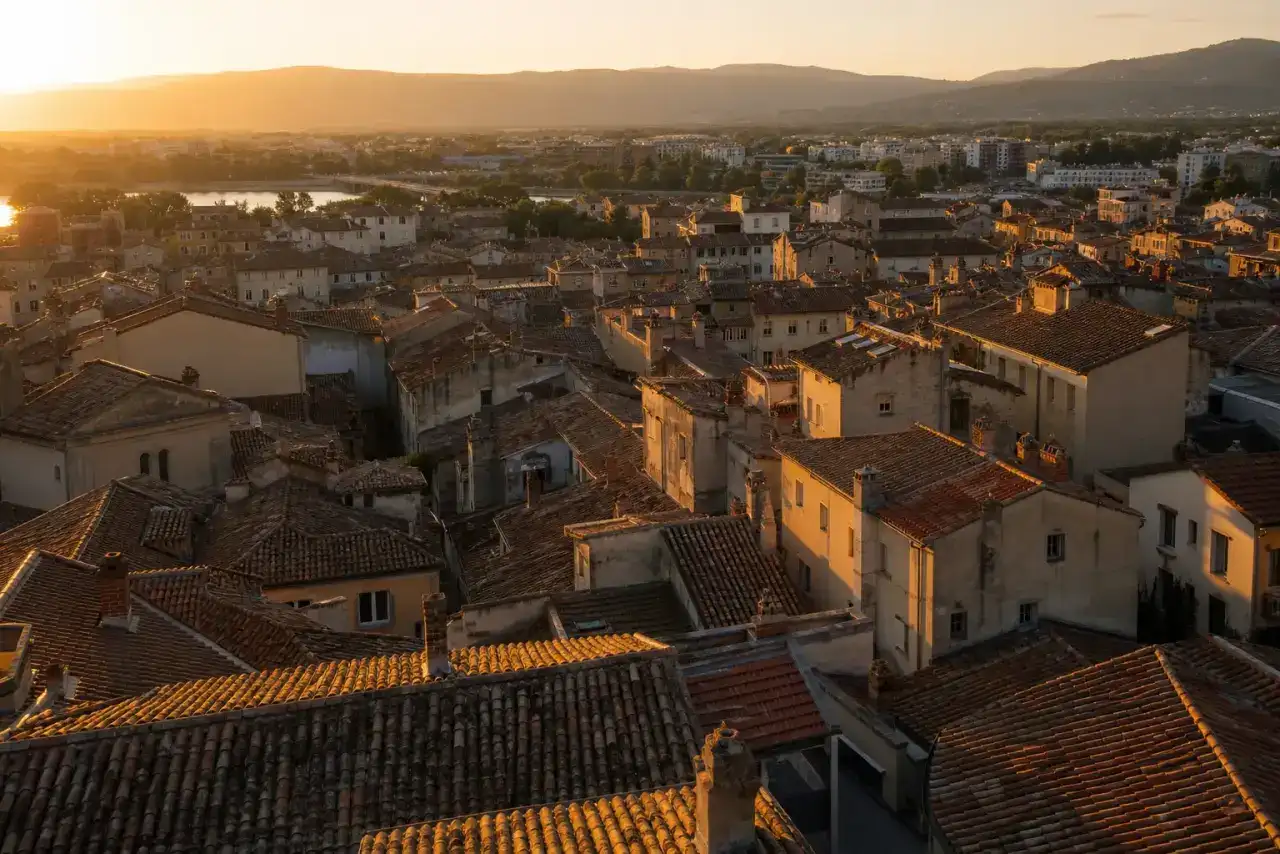 Toits du centre ancien de Valence en fin d'après-midi, tuiles romanes et façades aux enduits clairs, lumière rasante dorée, photographie réaliste